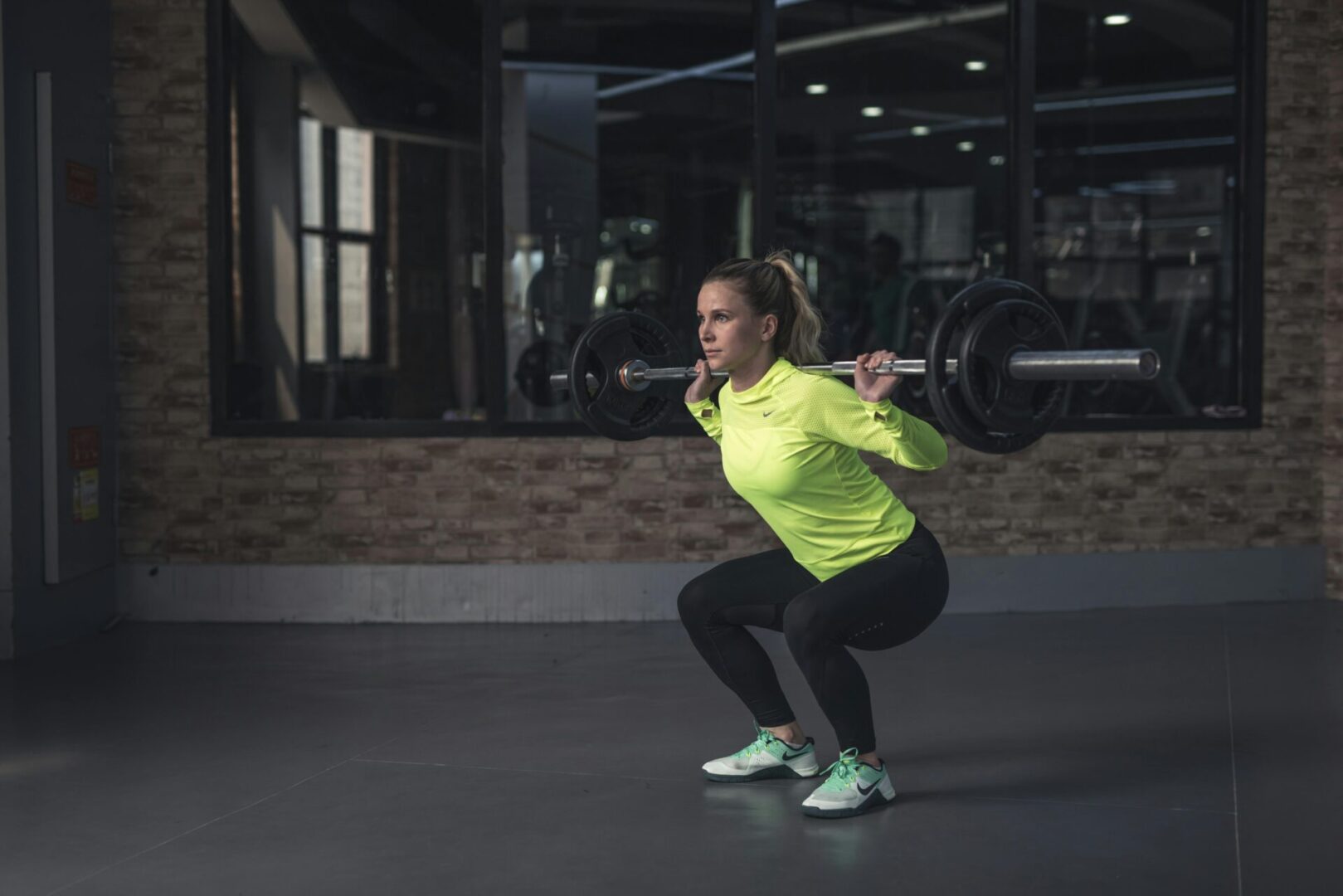A woman is squatting with a barbell in her hands.