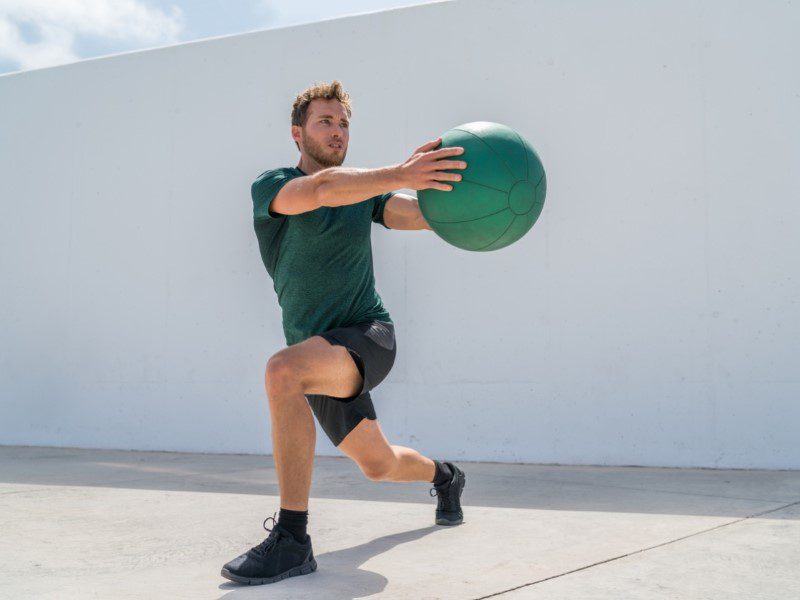 A man is doing squats with a ball