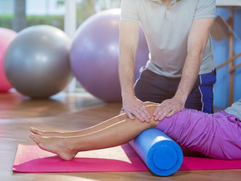 A person is rolling on the ground with a foam roller.